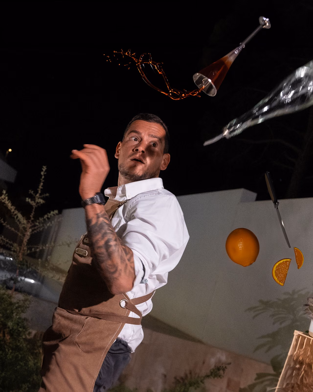 Manuel Scorza flairing with an orange mid-air at dusk behind the Sip n' Chill portable bar in Málaga