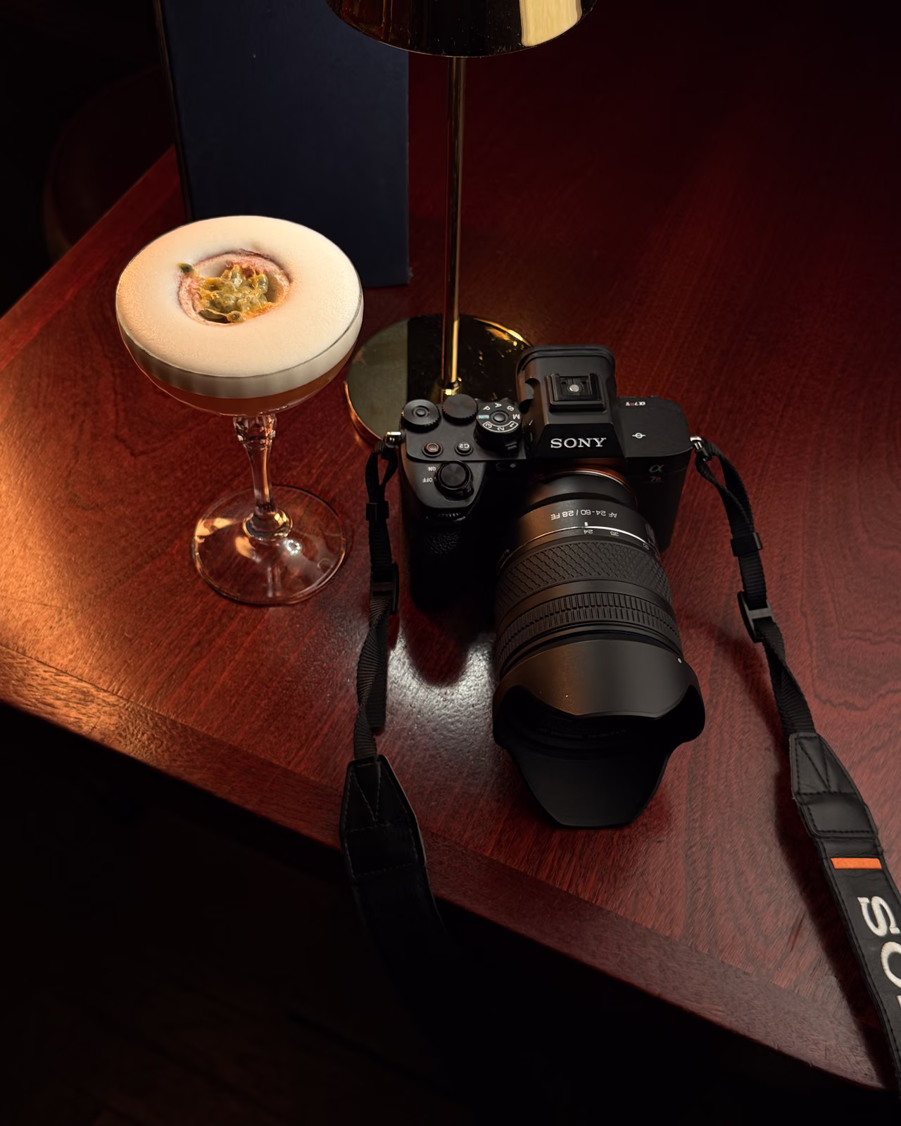 Sony camera and a passion fruit cocktail on a dark wood bar table in Edinburgh during the Fringe