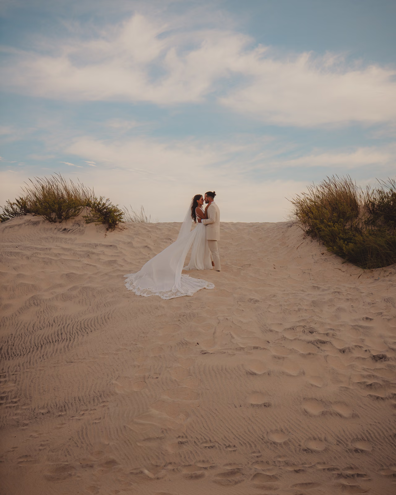 Bride and groom crossing the white dunes of Huelva under a wide evening sky, editorial wedding photography by Gorka Di Capitan