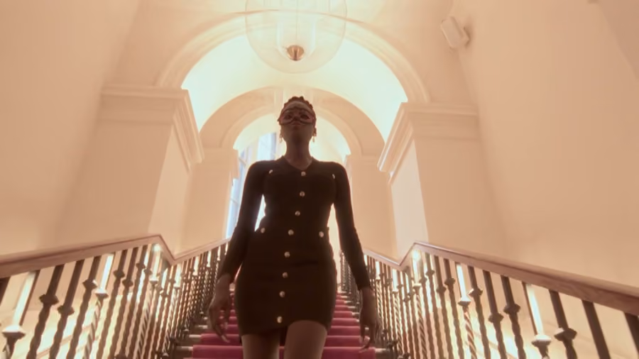 Guest in a masquerade mask descending a grand staircase at Be United's Motherland event