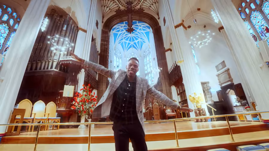 Performer with arms spread inside a cathedral for Kishaolin's Lord Almighty music video