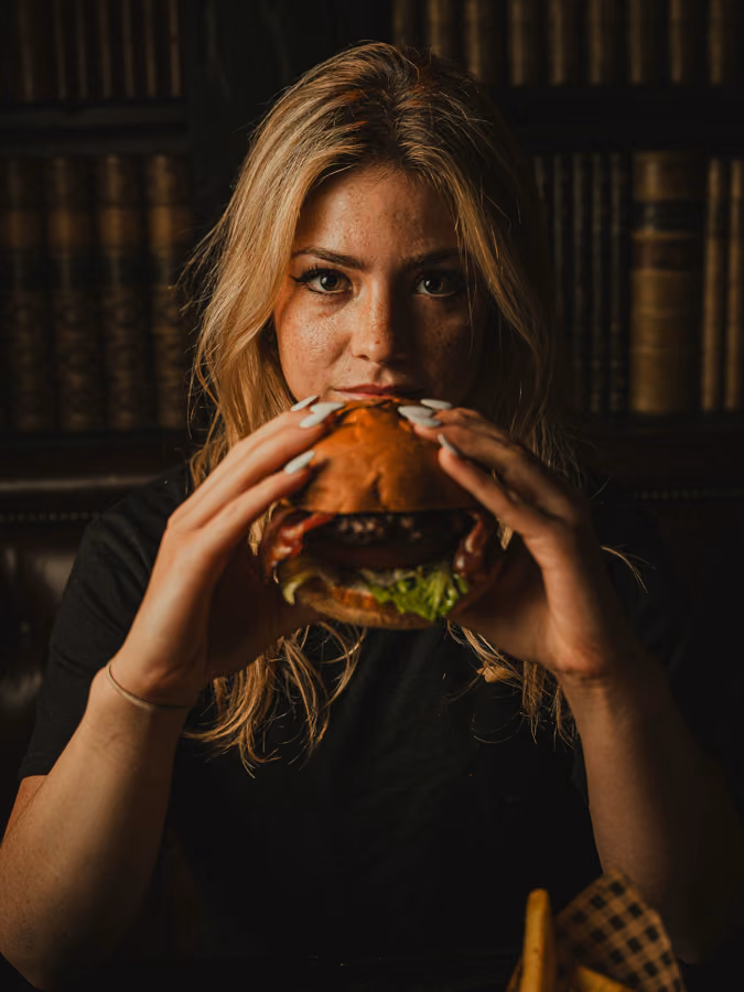 Guest biting into a burger in the library corner at Merchant Tavern, Edinburgh